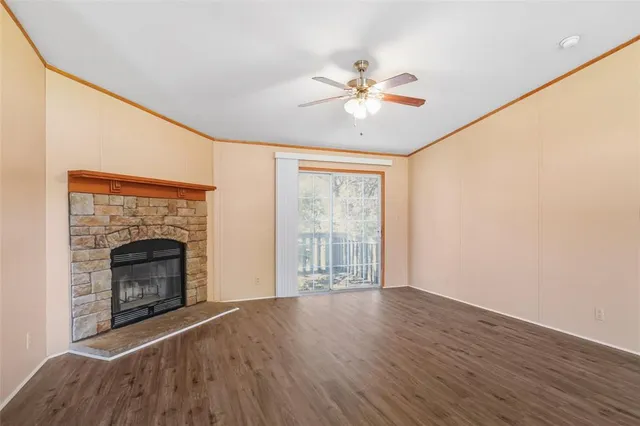 a view of an empty room with wooden floor and a fireplace