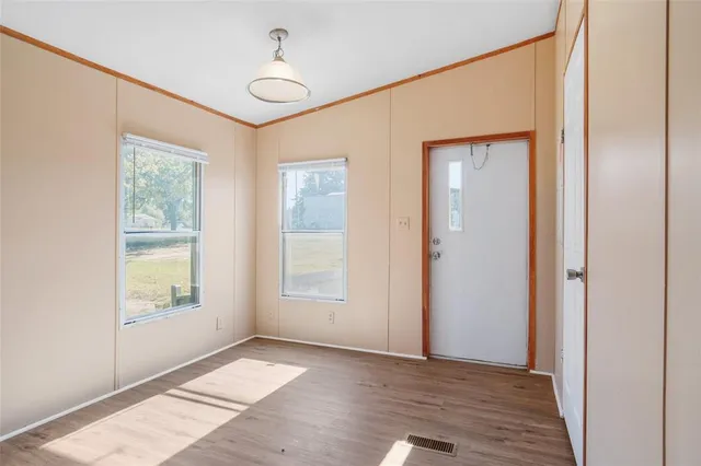 a view of an empty room with window and wooden floor