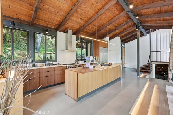 a large white kitchen with kitchen island a large window a sink and stainless steel appliances