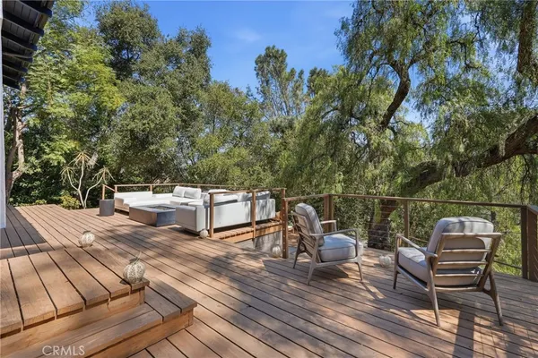 a view of a backyard with wooden floor and large trees