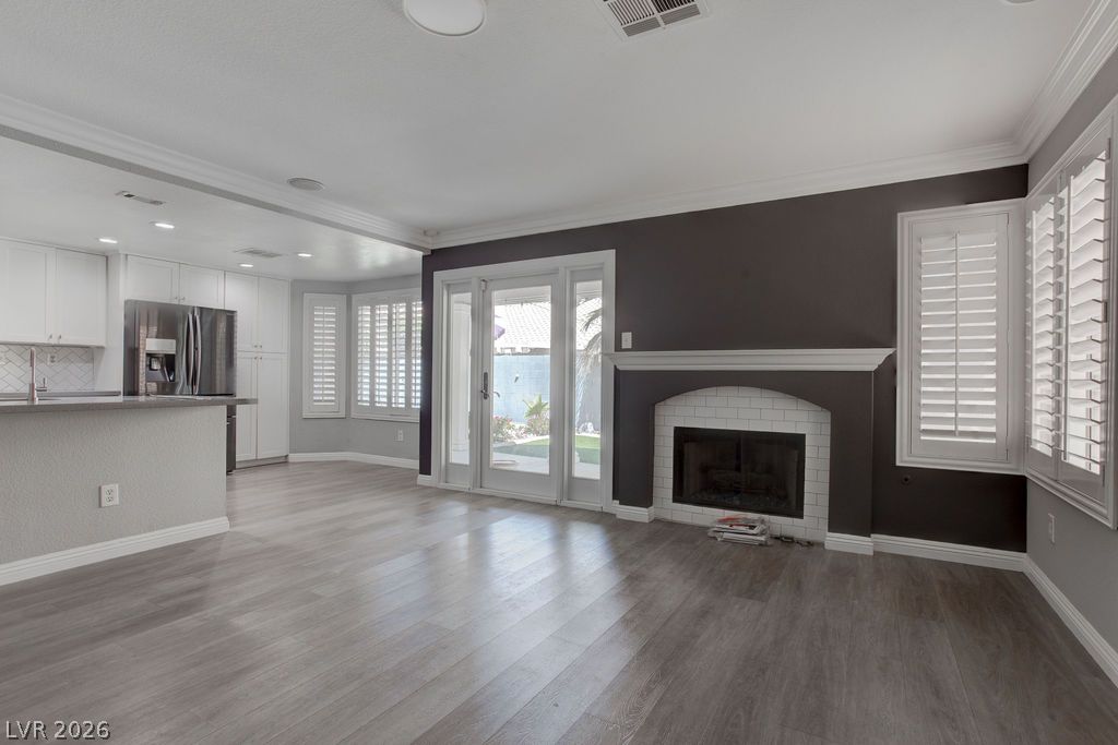 1416 Walstone Road North Las Vegas, NV 89031 - Photo 16 of 47 Open-concept living area with a fireplace, hardwood flooring, and french doors leading to a private yard.