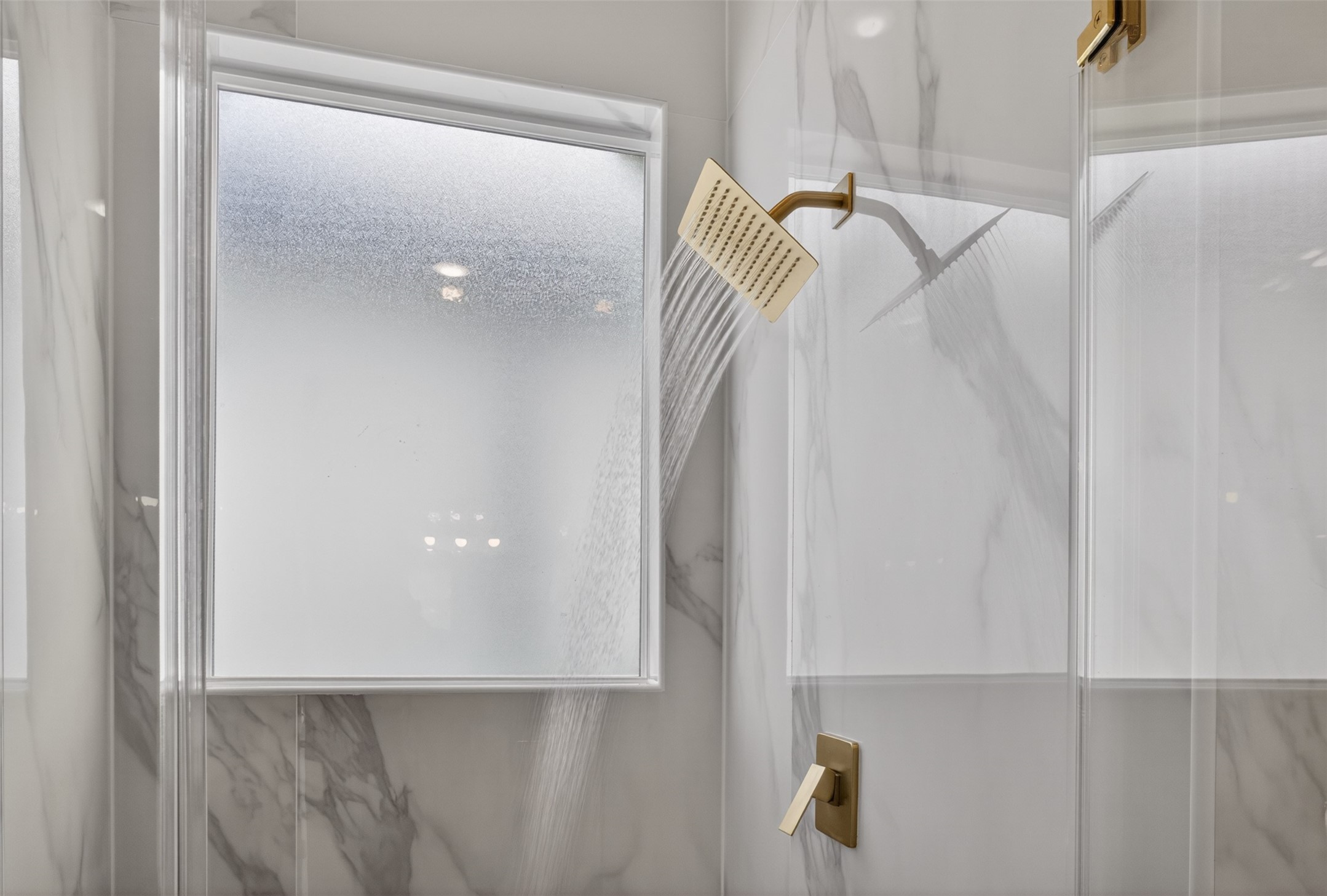 5906 St Augustine Street, Unit F Houston, TX 77021 - Photo 18 of 34 Separate shower with a marble-look surround, gold-tone rainfall fixture, and frosted window.