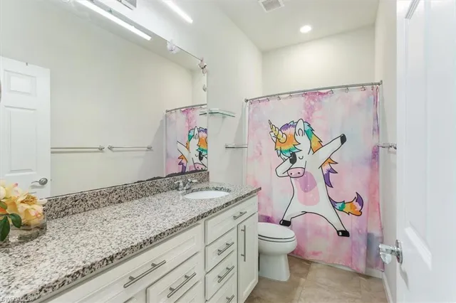 a bathroom with a granite countertop toilet sink and mirror