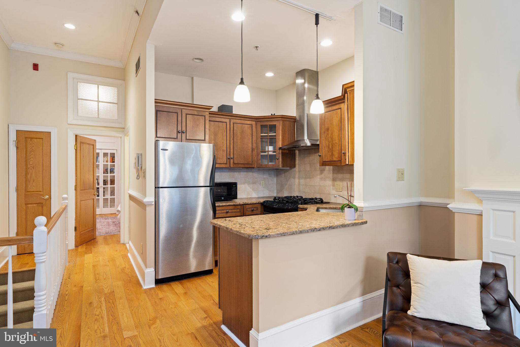 929 Clinton Street, Unit 1F Philadelphia, PA 19107 - Photo 15 of 41 a kitchen with stainless steel appliances granite countertop a refrigerator a oven a sink and a dining table with wooden floor