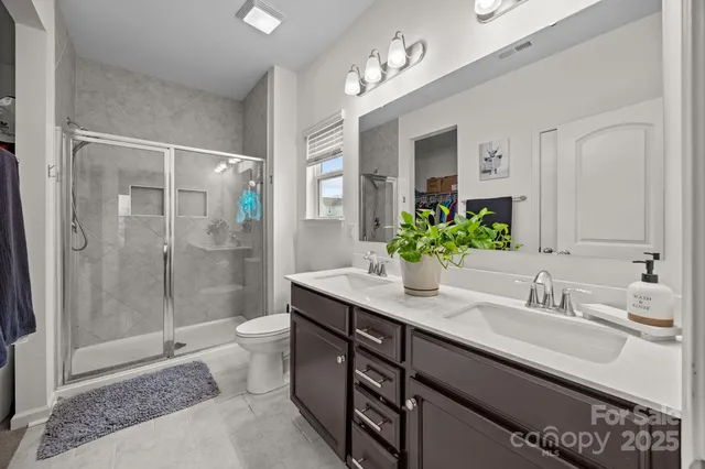 a bathroom with a granite countertop sink a toilet a mirror and shower