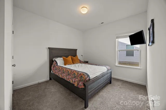 a bed sitting in a bedroom next to a window with a tv