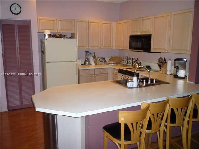 4070 Tree Top Road Cooper City, FL 33026 - Photo 3 of 12 a kitchen with a table chairs refrigerator and microwave