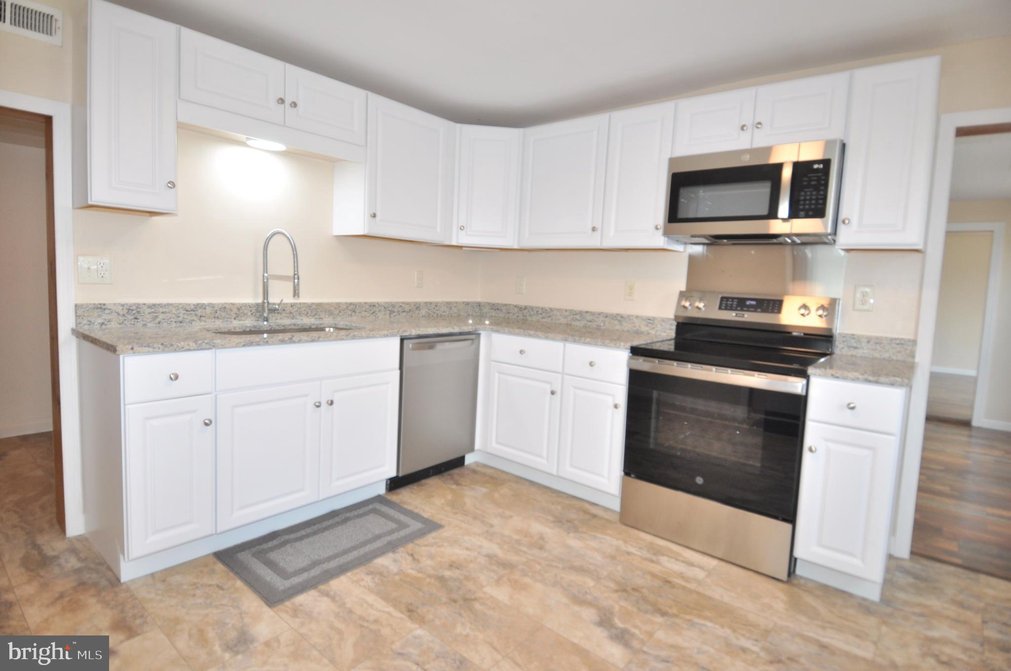 601 4th Street Pocomoke City, MD 21851 - Photo 9 of 35 a kitchen with granite countertop a stove top oven sink and cabinets