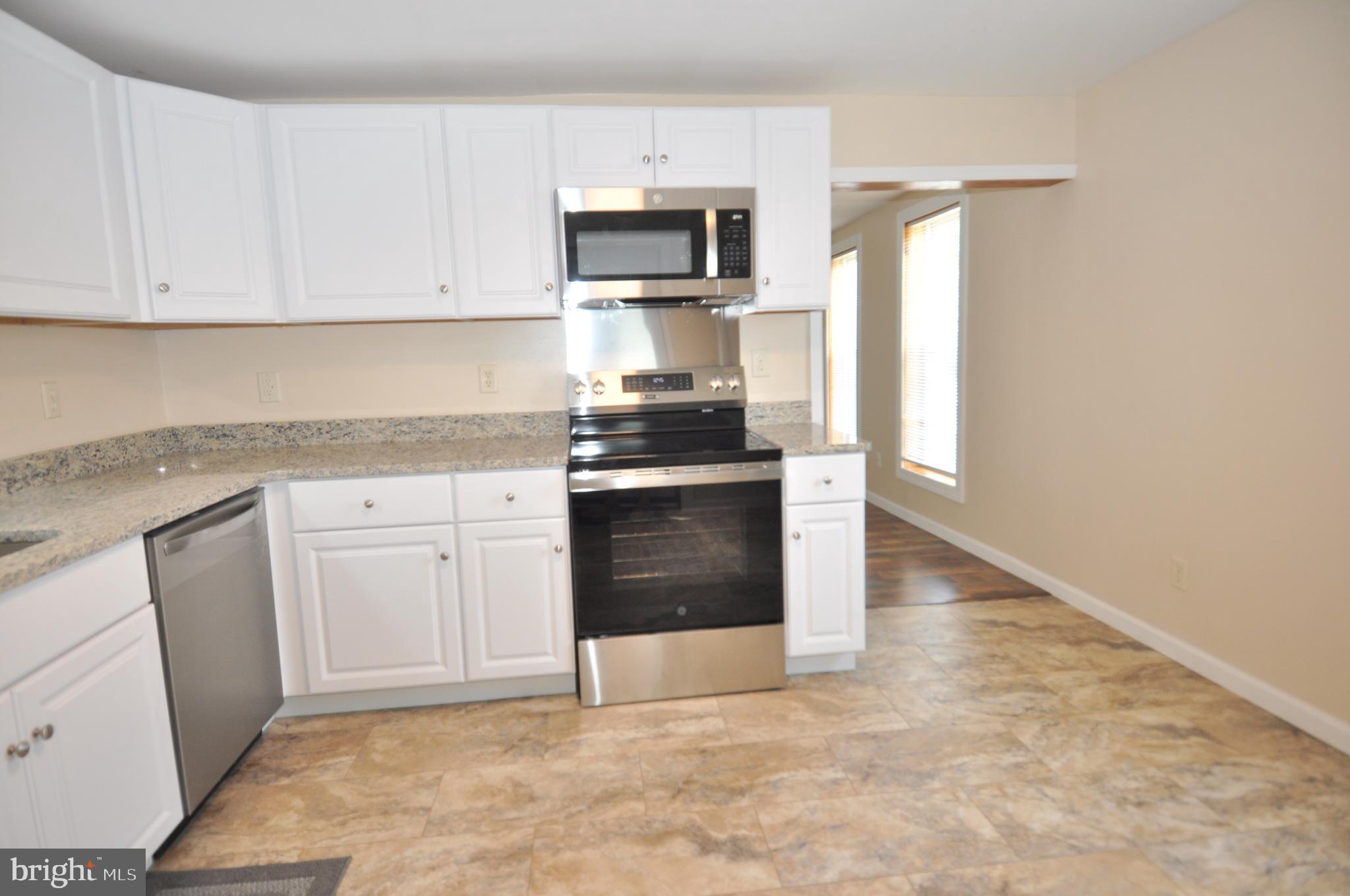 601 4th Street Pocomoke City, MD 21851 - Photo 10 of 35 a kitchen with granite countertop a stove top oven microwave and cabinets