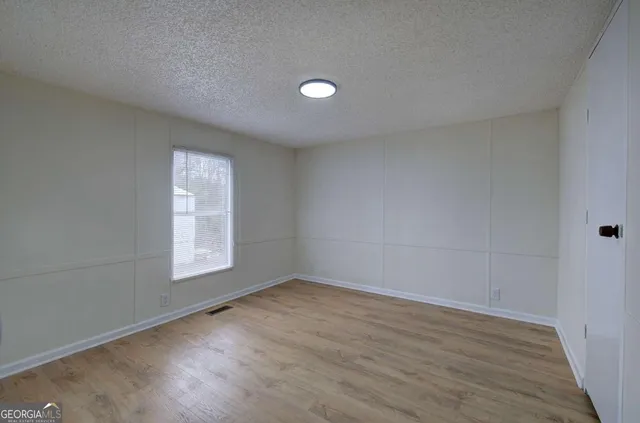 an empty room with wooden floor and windows