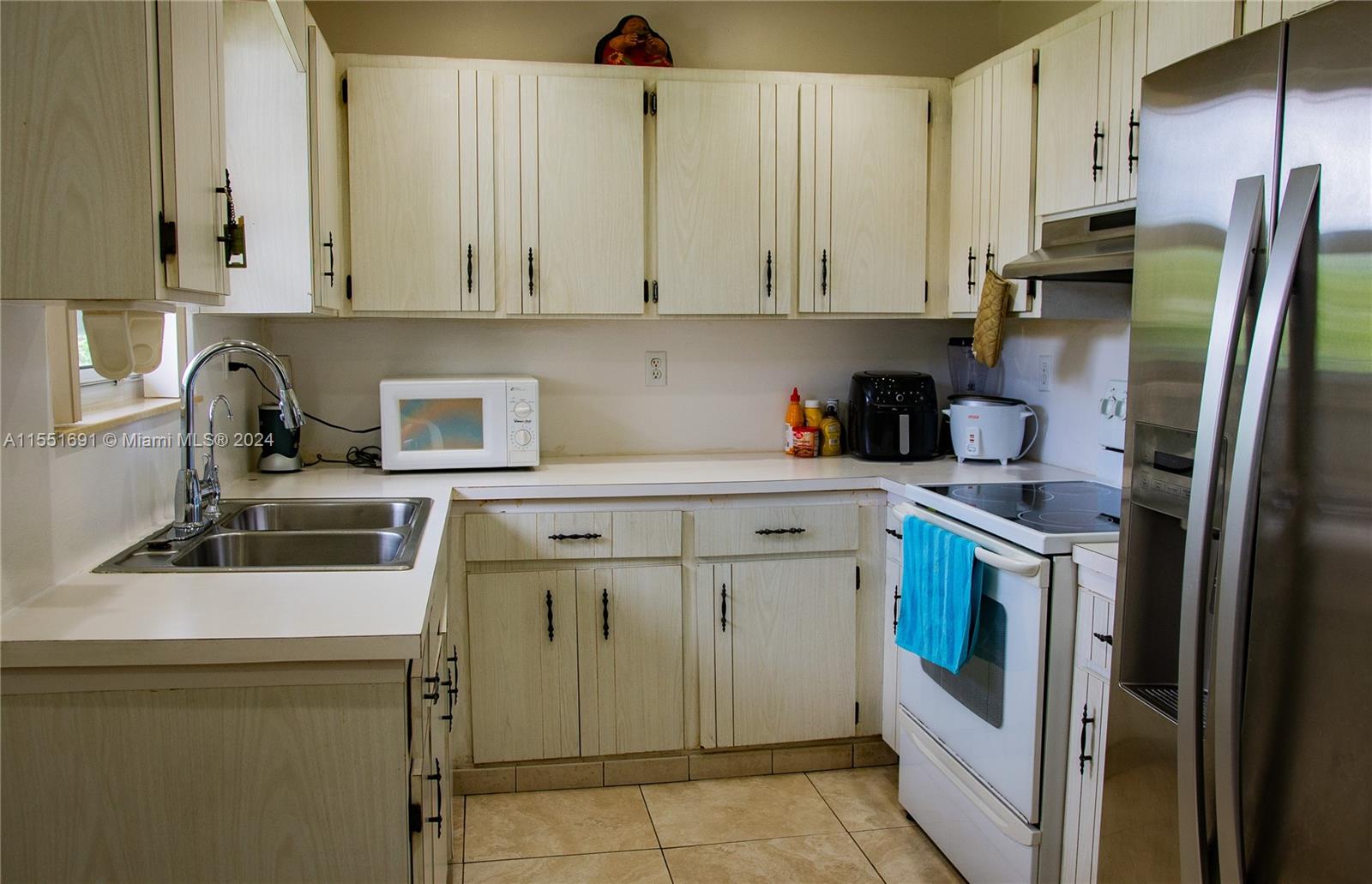 6005 Southwest 22nd Street Miami, FL 33155 - Photo 13 of 36 a kitchen with stainless steel appliances granite countertop a sink a stove a refrigerator and white cabinets