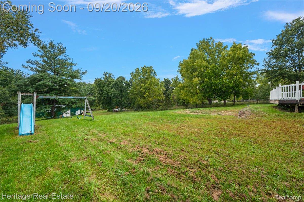3337 Le Valley Road Columbiaville, MI 48421 - Photo 4 of 57 Expansive grassy yard with mature trees and a raised deck with white railings