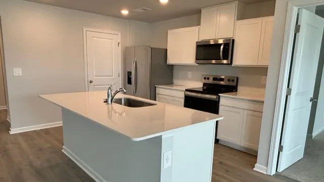 a kitchen with stainless steel appliances a sink a stove a refrigerator a center island and cabinets