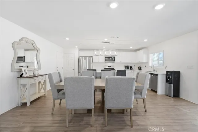 a view of a dining room and livingroom with furniture wooden floor a rug a fireplace and a chandelier