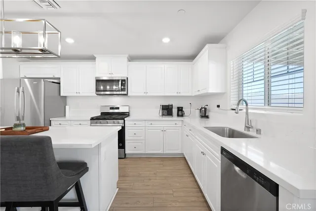 a kitchen with stainless steel appliances granite countertop a sink a stove a refrigerator cabinets and a chairs