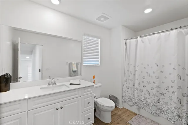 a bathroom with a granite countertop toilet a sink a mirror a window and vanity