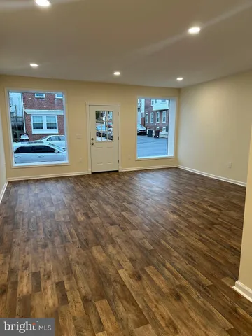 an empty room with kitchen view and wooden floor