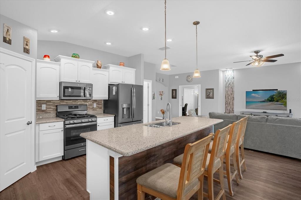 3782 Arlington Ridge Boulevard Leesburg, FL 34748 - Photo 8 of 52 a kitchen with stainless steel appliances kitchen island granite countertop a table chairs stove and microwave