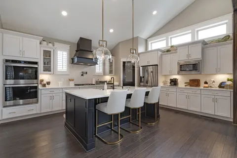 a kitchen with stainless steel appliances kitchen island granite countertop a stove a sink a microwave a center island and a cabinets