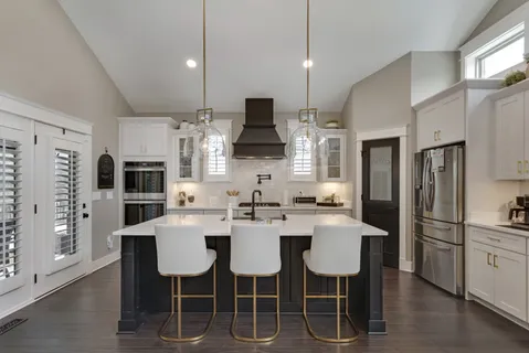 a kitchen with stainless steel appliances kitchen island granite countertop a dining table chairs and a refrigerator