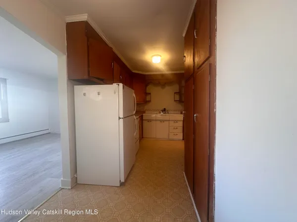 a view of a refrigerator in kitchen and an empty room