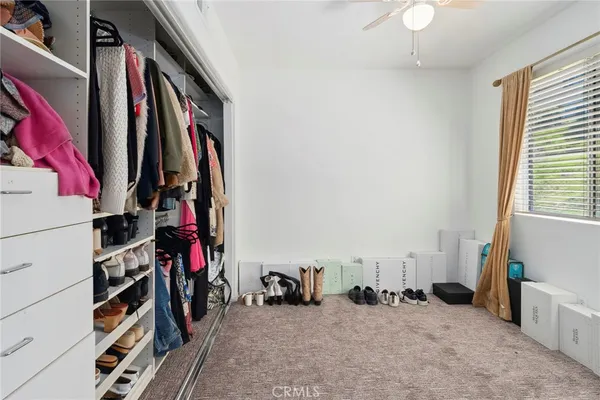 a view of walk in closet with clothes and shoes