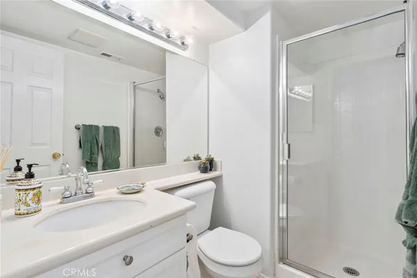 a bathroom with a sink a toilet a mirror and shower