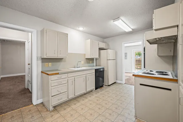 a kitchen with granite countertop a refrigerator and a stove top oven