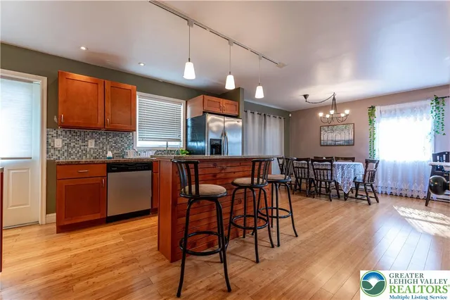 a kitchen with stainless steel appliances granite countertop a kitchen island a stove a cabinets a sink and a chairs
