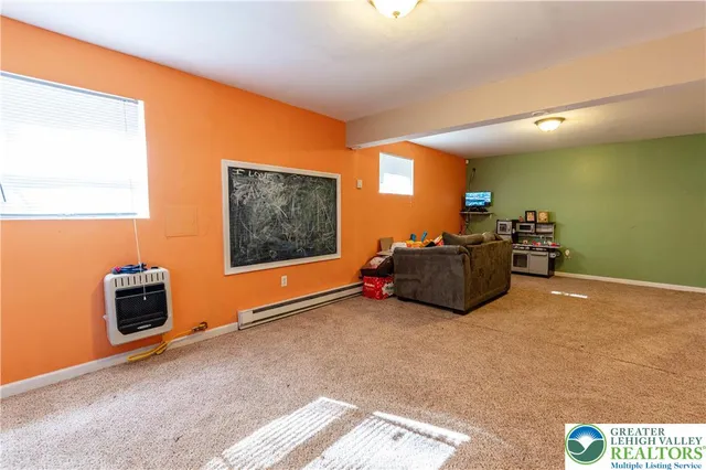 a living room with furniture a flat screen tv and a refrigerator