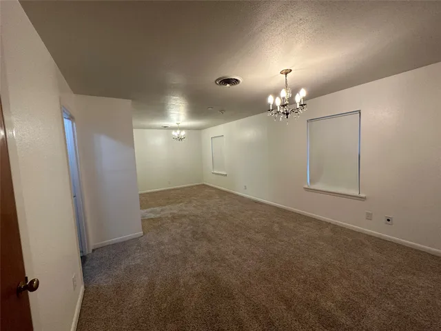 en empty room with chandelier fan and refrigerator