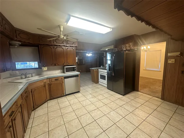 a kitchen with stainless steel appliances kitchen island granite countertop a refrigerator and a sink