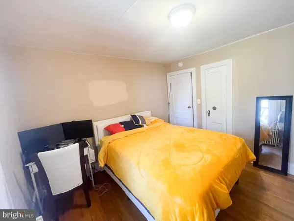 a bed sitting in a bedroom next to a window with chair and wooden floor