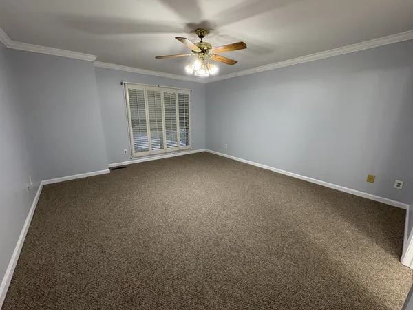 an empty room with a chandelier fan and windows