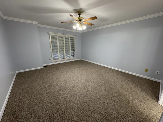 an empty room with a chandelier fan and windows