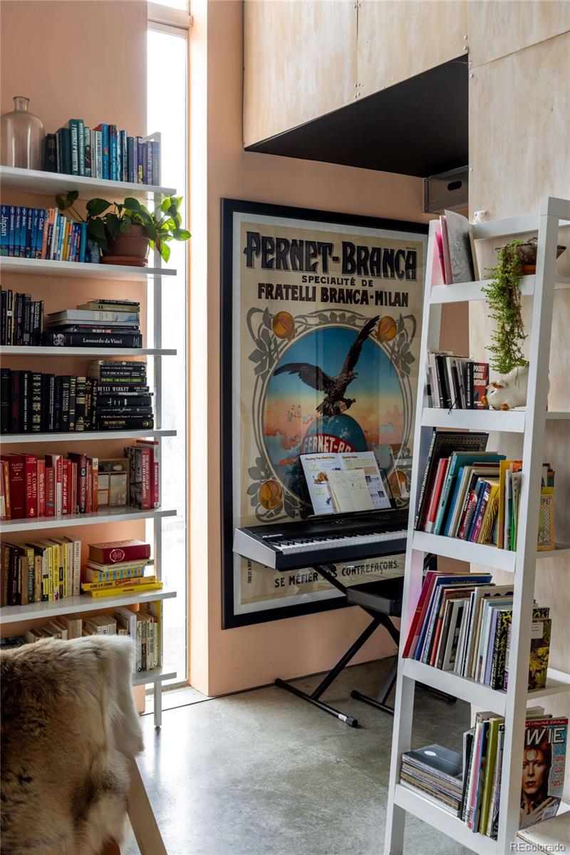 3457 Ringsby Court, Unit 306 Denver, CO 80216 - Photo 16 of 38 a living room with lots of books and a book shelf