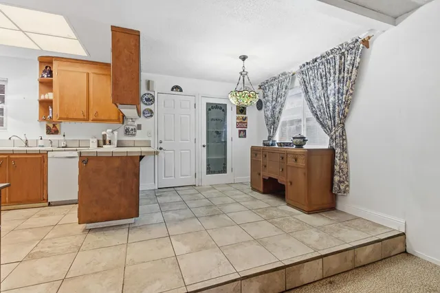 a kitchen with stainless steel appliances a sink a stove a refrigerator a washer dryer and white cabinets