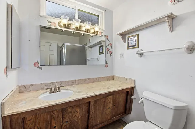 a bathroom with a granite countertop sink a toilet and mirror