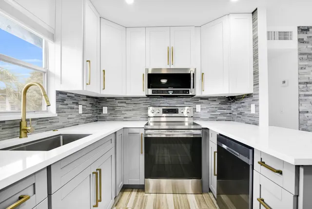 a kitchen with stainless steel appliances granite countertop a stove top oven a sink dishwasher and a refrigerator with wooden cabinets