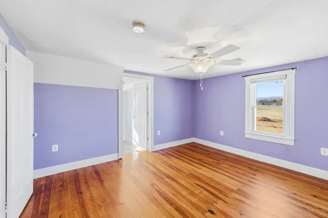 wooden floor in an empty room with a chandelier fan