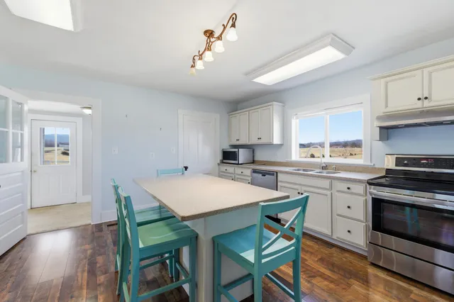 a kitchen with a table chairs refrigerator and wooden floor