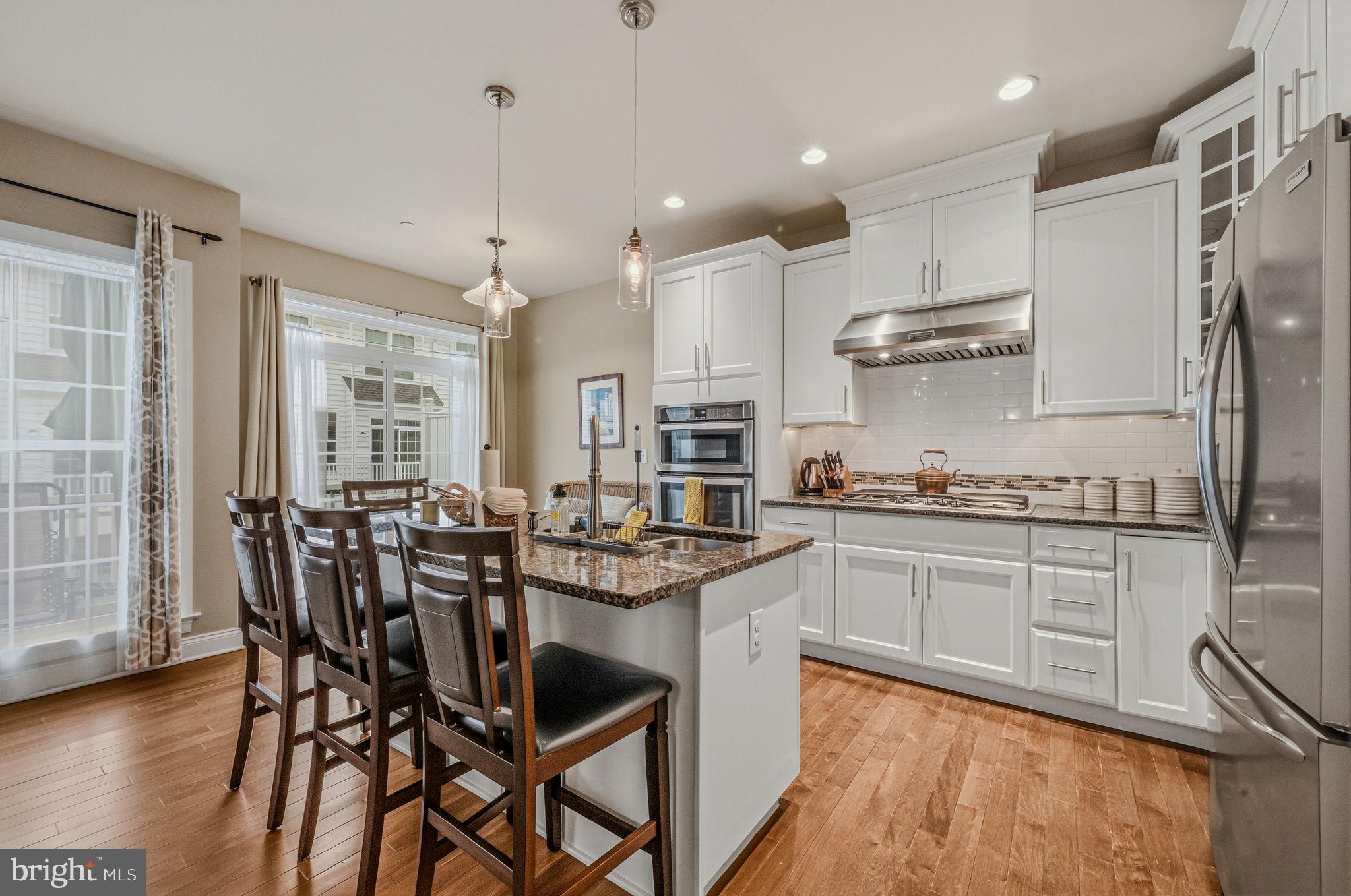 208 Jackdaw Alley, Unit 208 Springfield, PA 19064 - Photo 6 of 41 a kitchen with stainless steel appliances granite countertop a table chairs stove and wooden cabinets