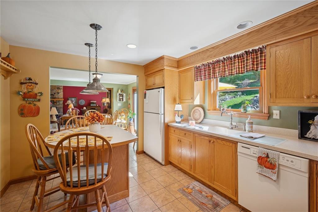 4941 Bulltown Road Murrysville, PA 15668 - Photo 14 of 39 a kitchen with stainless steel appliances granite countertop a sink dishwasher a dining table and chairs with wooden floor