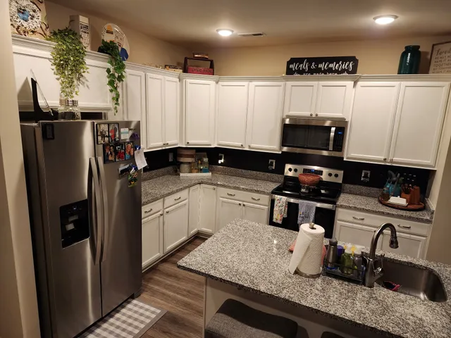 a kitchen with stainless steel appliances granite countertop a sink refrigerator and microwave