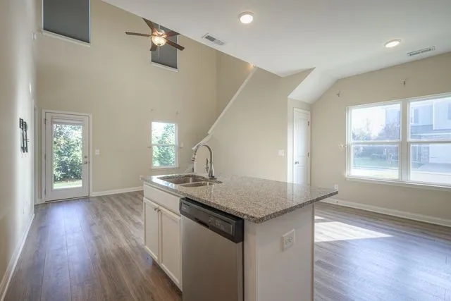 a kitchen with stainless steel appliances granite countertop a sink a stove and wooden floor