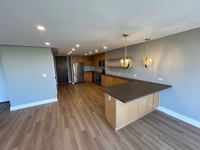 720 West Gordon Terrace, Unit 6D Chicago, IL 60613 - Photo 6 of 28 a kitchen with stainless steel appliances granite countertop a stove a refrigerator and a microwave oven on the wooden floor