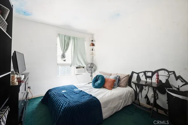 a bedroom with a bed next to a window and desk