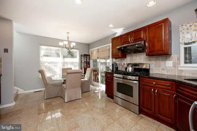 a kitchen with stainless steel appliances granite countertop a stove top oven a sink dishwasher a dining table and chairs with wooden floor