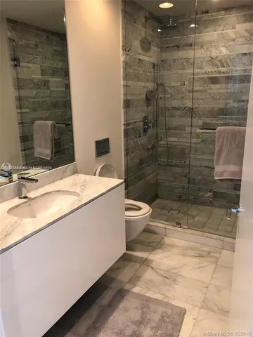 a bathroom with a granite countertop sink a toilet and shower