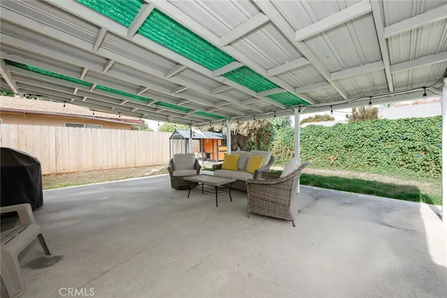 a view of a patio with table and chairs under an umbrella with a small yard
